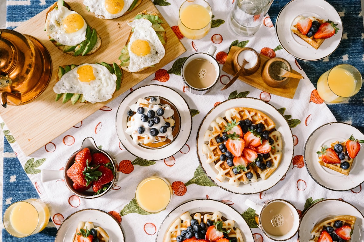 Golden breakfast spread with pancakes, fresh fruit, and coffee on a bright table
