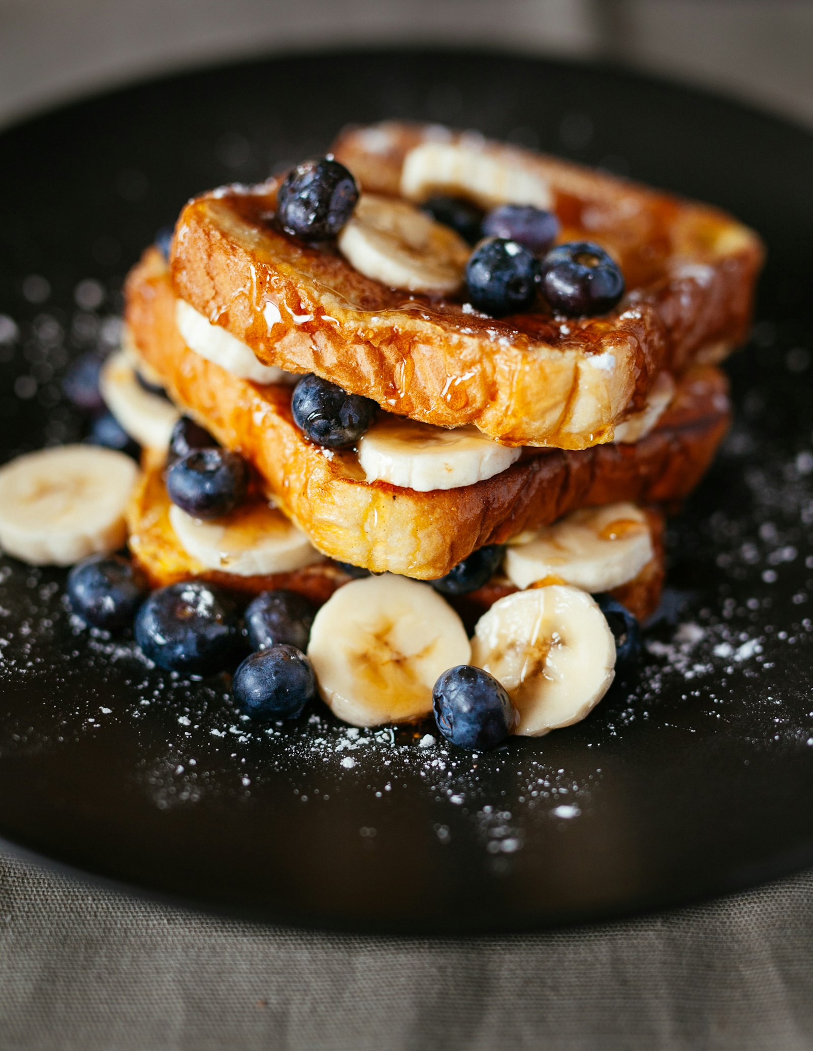 Slices of golden French toast dusted with powdered sugar and topped with berries