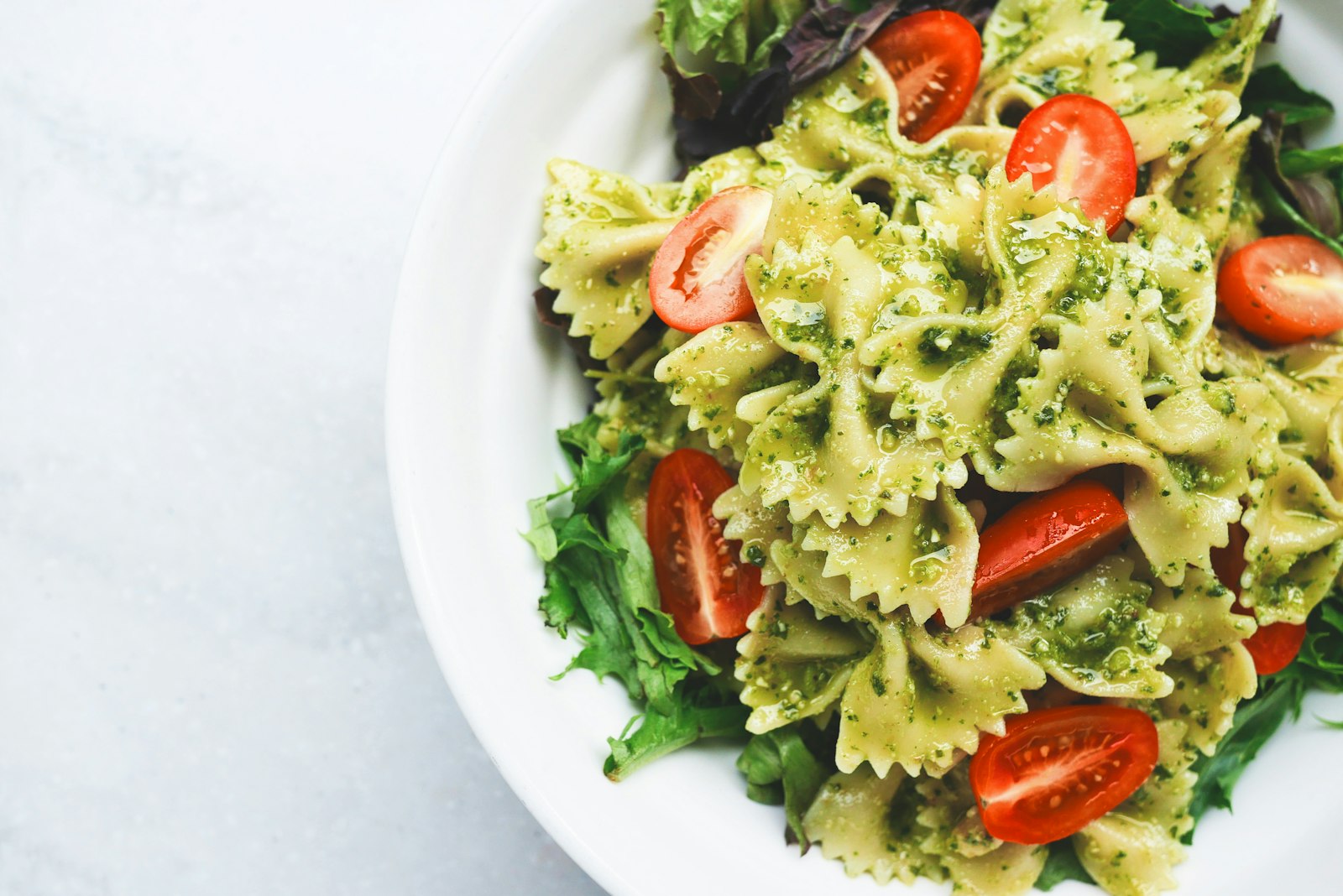 Bowl of pasta tossed with bright green basil pesto and Parmesan